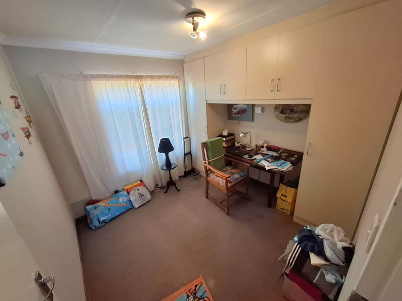 A functional bedroom featuring built-in cupboards and carpeted flooring, offering a practical layout with natural light from the window.