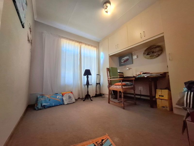 A bedroom featuring built-in cupboards and carpeted flooring, offering a functional space with potential for modernization.