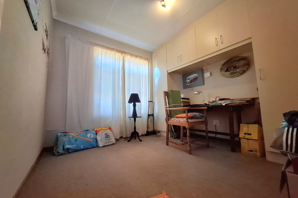 A bedroom featuring built-in cupboards and carpeted flooring, offering a functional space with potential for modernization.