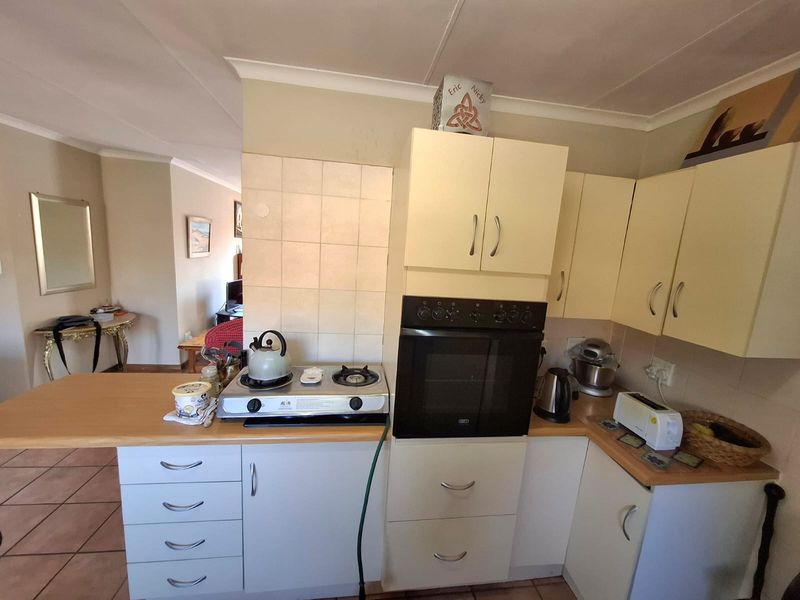 A functional kitchen featuring built-in cabinetry, a wall-mounted oven, gas cooktop, and tiled splashback, opening into the adjacent living area.