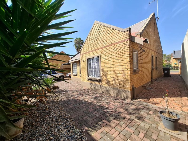 Front view of a face brick house featuring a paved driveway and secure window bars.