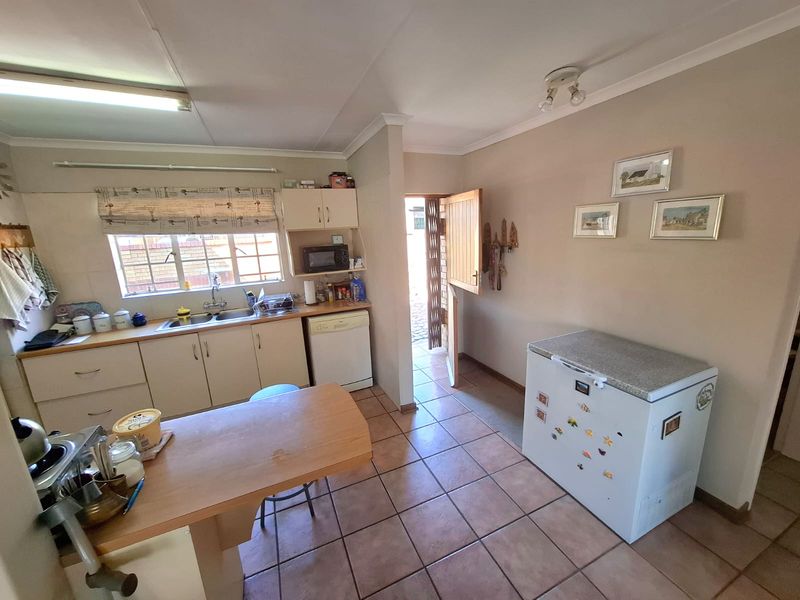 A functional kitchen featuring tiled flooring, built-in cabinetry, a double basin sink, and a stable door providing direct access to the exterior.