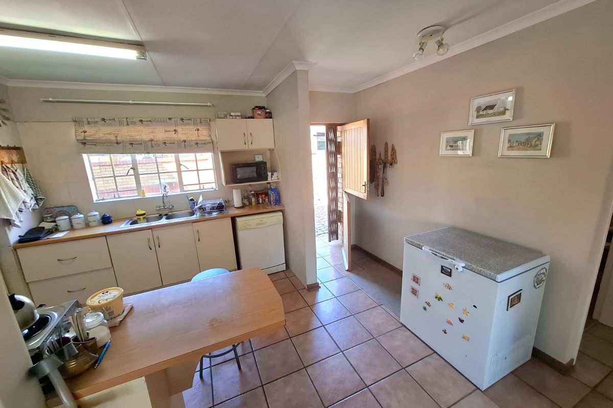 A functional kitchen featuring tiled flooring, built-in cabinetry, a double basin sink, and a stable door providing direct access to the exterior.