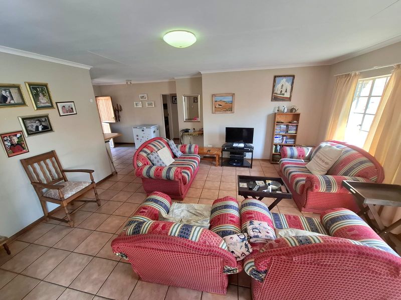 Spacious living room featuring neutral wall tones, tiled flooring, and coved cornicing, offering a comfortable and functional layout for relaxation.