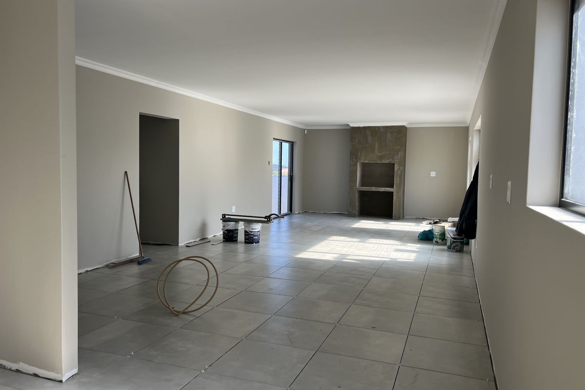 Spacious open-plan living area featuring large format floor tiles, a built-in fireplace, and sliding door access to the exterior.