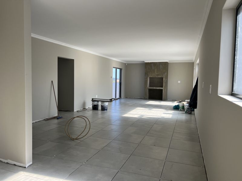 Spacious open-plan living area featuring large format floor tiles, a built-in fireplace, and sliding door access to the exterior.