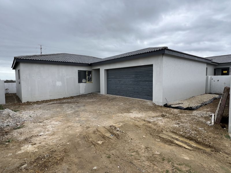 Front exterior view of a modern house featuring a tiled roof, plastered walls, and a roller garage door, currently undergoing final site completion.