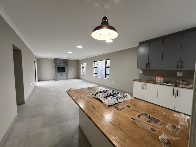 Spacious open-plan living and kitchen area featuring modern cabinetry, a large wooden island with a gas hob, and a built-in fireplace.