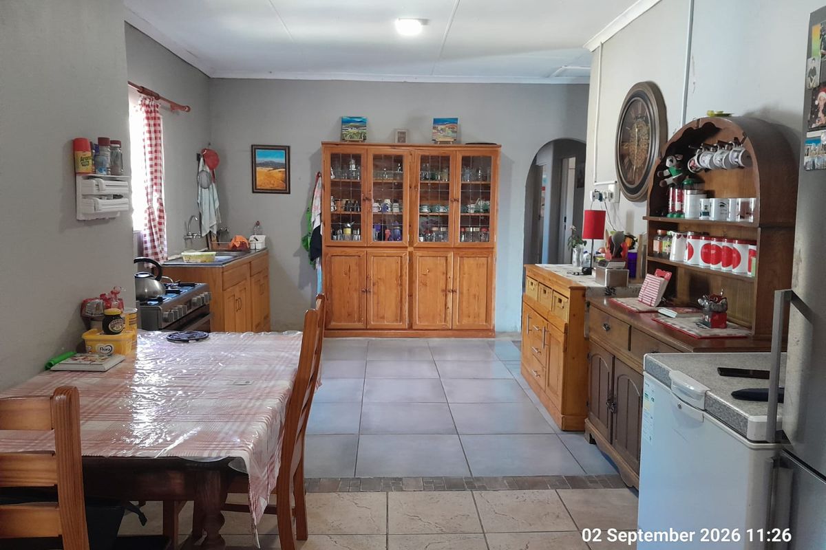 A functional kitchen area featuring tiled flooring, built-in wooden cabinetry, and integrated cooking appliances, offering a practical layout for daily meal preparation.