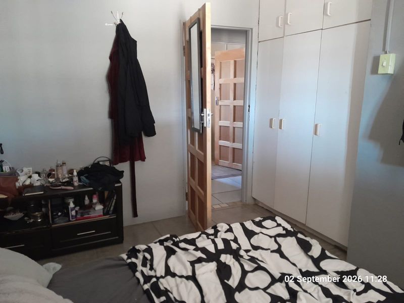 A bedroom featuring built-in cupboards and a wooden door leading to an adjacent room.