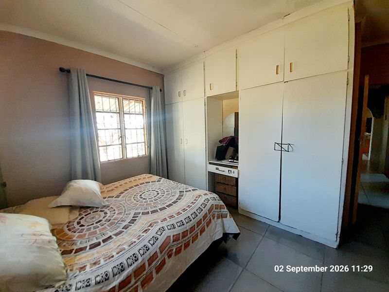 Bedroom featuring built-in cupboards with integrated vanity, tiled flooring, and security bars on the window.