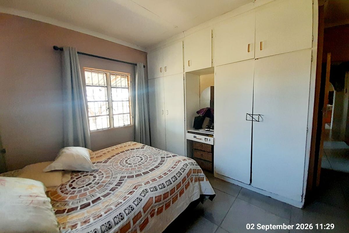 Bedroom featuring built-in cupboards with integrated vanity, tiled flooring, and security bars on the window.