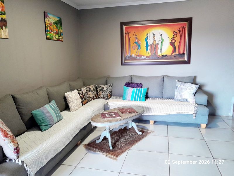 A comfortable living room featuring neutral wall tones and light-colored floor tiles, providing a clean and functional space.
