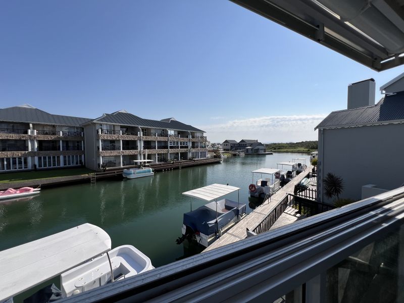 A scenic view overlooking a tranquil canal with private jetties, boats, and surrounding residential apartment buildings.