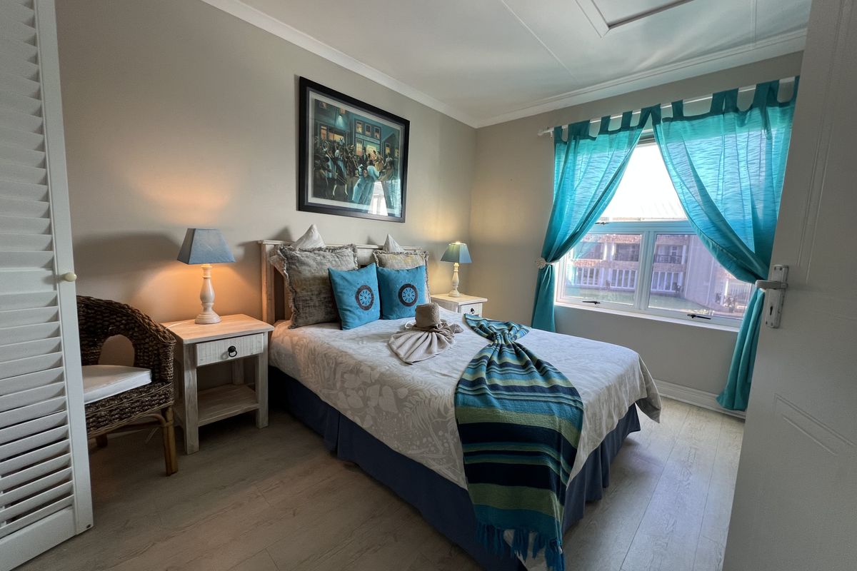 A well-maintained bedroom featuring light-toned laminate flooring, a built-in cupboard, and a window with natural light.