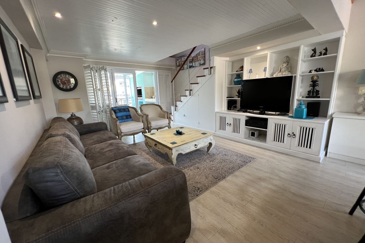 Spacious living room featuring built-in cabinetry, a staircase, and light-toned laminate flooring, with direct access to an outdoor patio area.