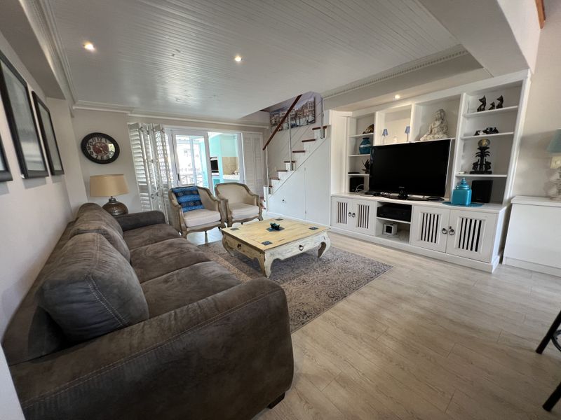 Spacious living room featuring built-in cabinetry, a staircase, and light-toned laminate flooring, with direct access to an outdoor patio area.