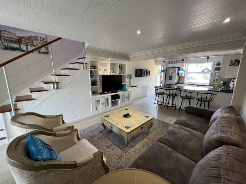 Spacious open-plan living area featuring a modern kitchen with island seating, built-in cabinetry, and a staircase leading to the upper level.