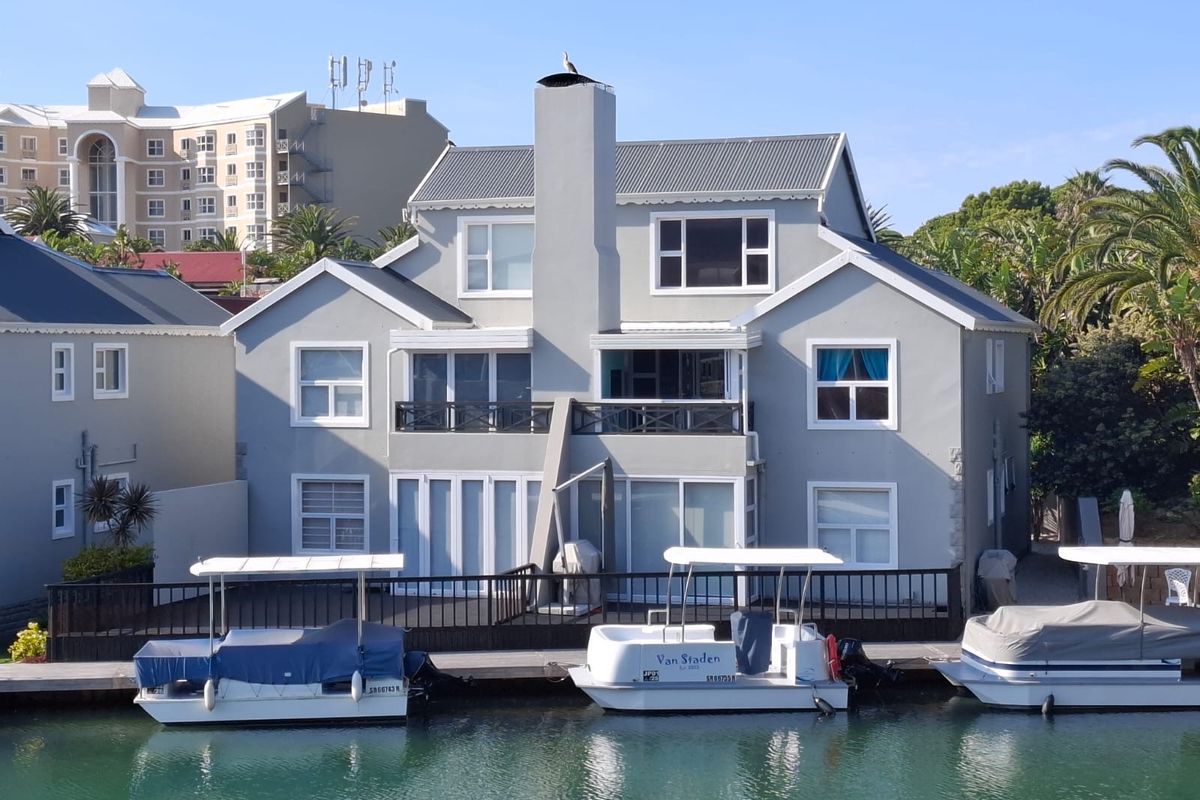 Rear view of a multi-story apartment building featuring a private jetty, timber decking, and balcony access overlooking the water.