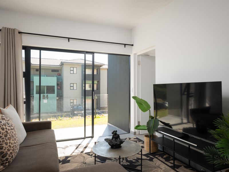 A bright living room featuring a large sliding glass door that provides access to an outdoor area and allows for ample natural light.