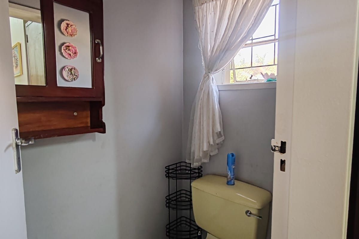 A compact bathroom featuring a toilet, tiled flooring, and a wall-mounted medicine cabinet, requiring cosmetic updates to modernize the space.