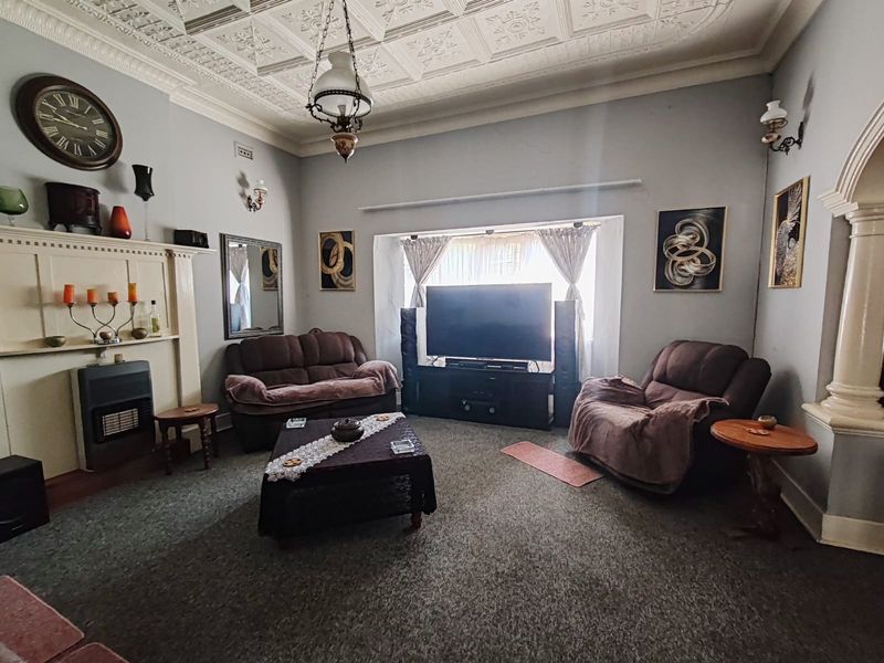 Spacious living room featuring a classic ornate pressed metal ceiling, a traditional fireplace mantel, and an elegant archway detail.