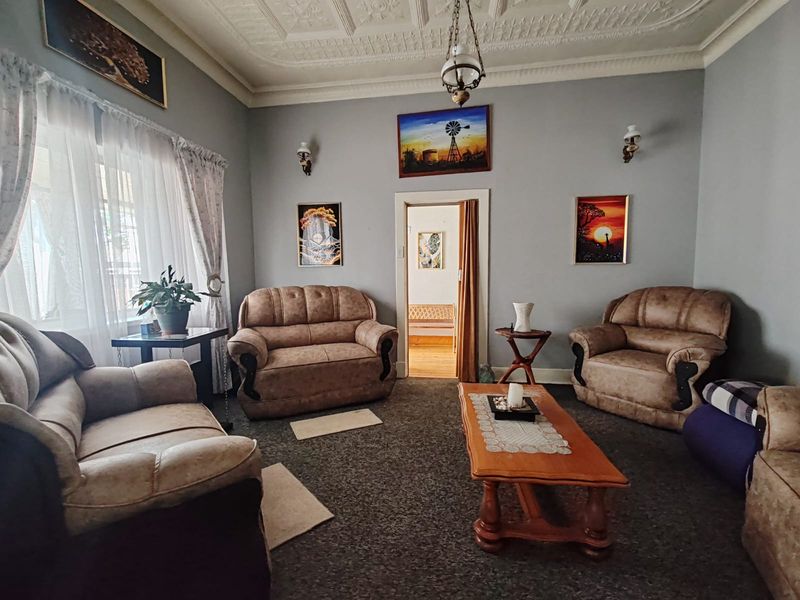 A traditional living room featuring an ornate pressed metal ceiling, wall sconces, and classic architectural detailing.