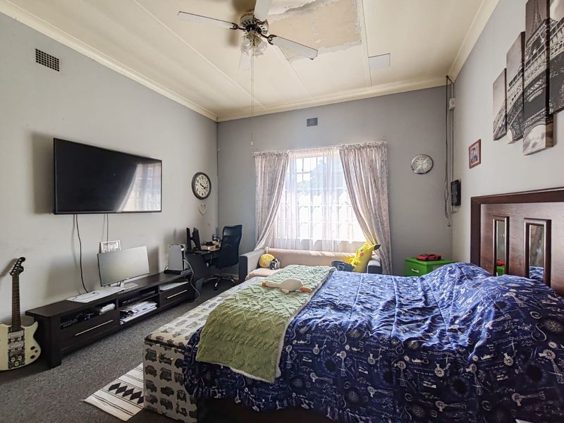 Spacious bedroom featuring a ceiling fan and window, currently requiring ceiling repairs to address visible plaster damage.