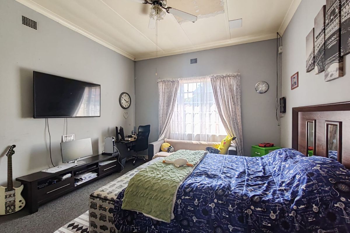 Spacious bedroom featuring a ceiling fan and window, currently requiring ceiling repairs to address visible plaster damage.