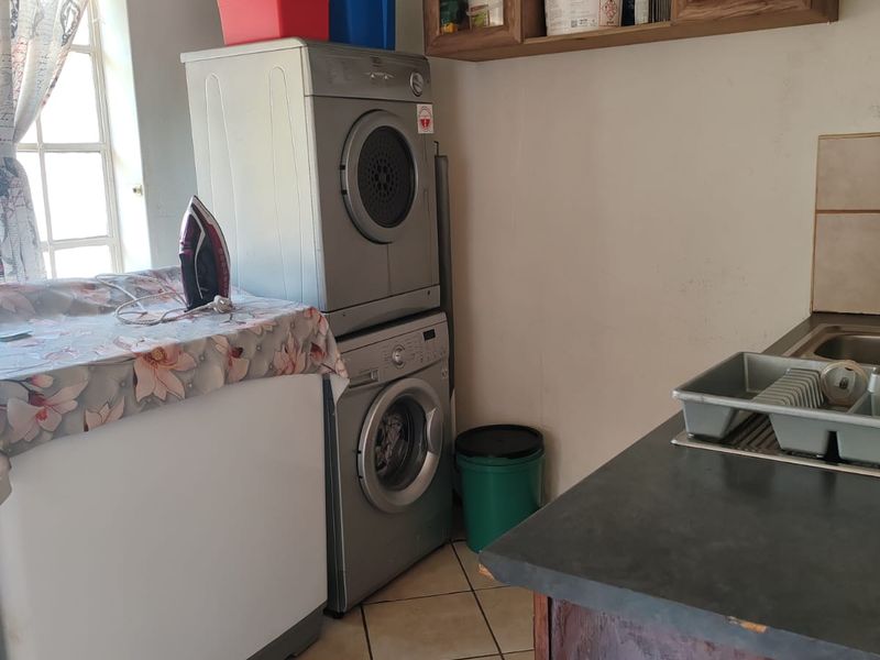 A functional laundry area featuring built-in cabinetry, tiled flooring, and a countertop with an integrated sink.