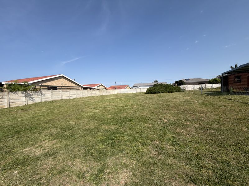 A spacious, level residential plot featuring a well-maintained lawn and secure precast concrete boundary walls.