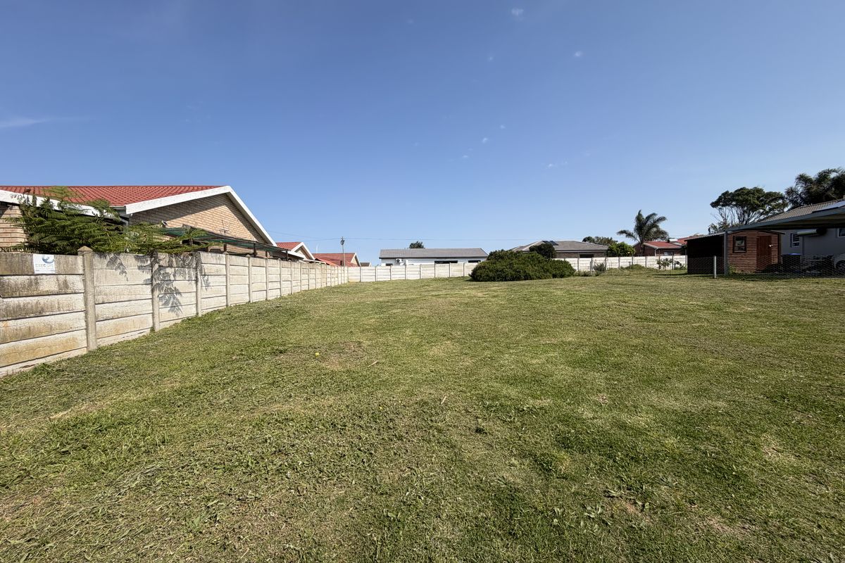 A vacant residential plot featuring a well-maintained lawn and secure precast concrete boundary walls, offering a clear space for future development.