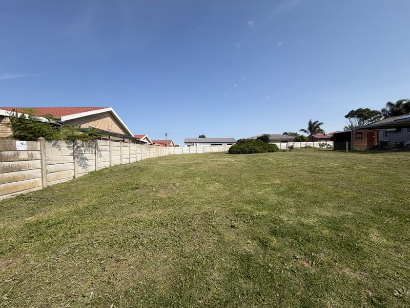 A vacant residential plot featuring a well-maintained lawn and secure precast concrete boundary walls, offering a clear space for future development.