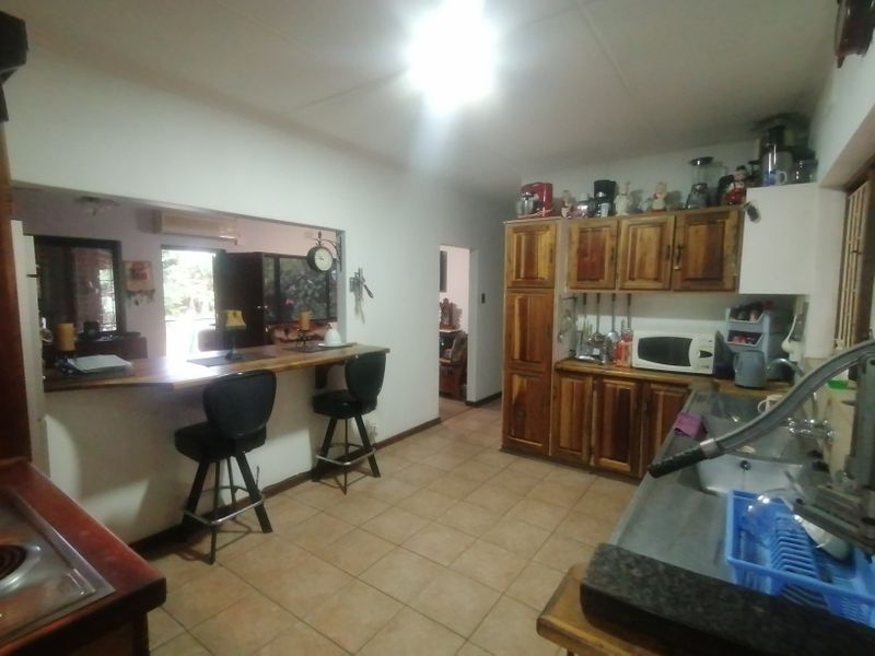 A functional kitchen featuring wooden cabinetry, a breakfast bar, and a pass-through window connecting to the adjacent living area.