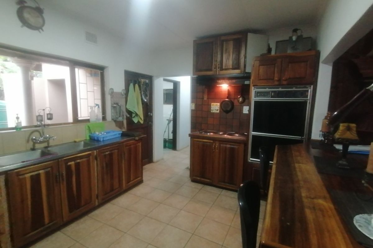 A functional kitchen featuring wooden cabinetry, built-in oven, cooktop, and tiled flooring, offering a traditional layout with ample storage space.
