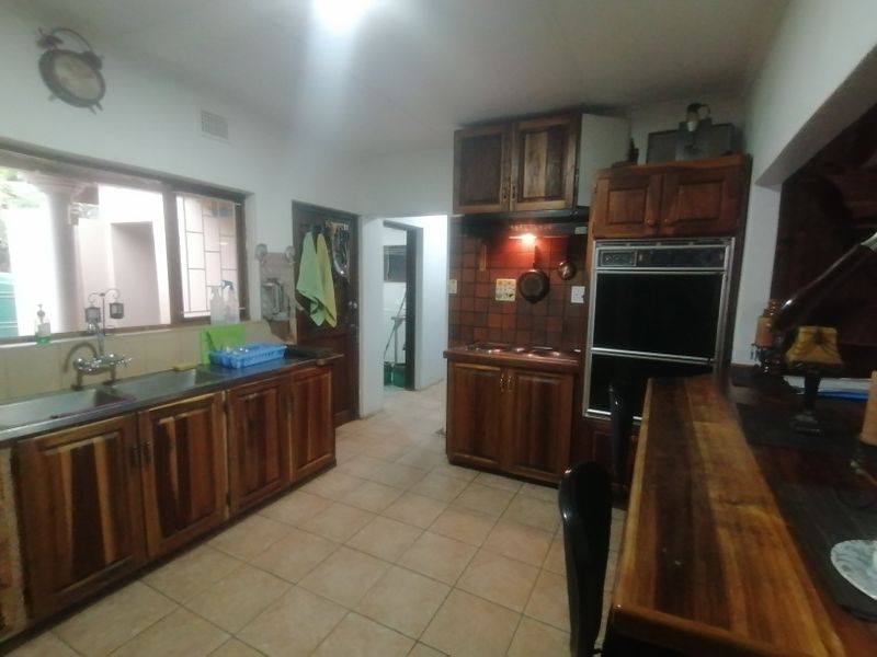 A functional kitchen featuring wooden cabinetry, built-in oven, cooktop, and tiled flooring, offering a traditional layout with ample storage space.