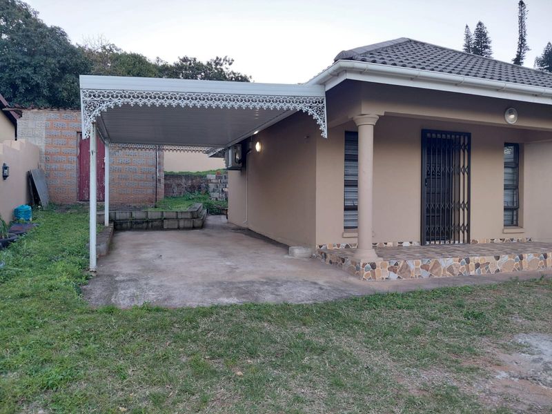 Front view of the property featuring a covered carport, tiled veranda, and secure entrance with security gate.