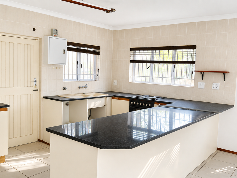 A functional kitchen featuring granite countertops, built-in stove, tiled splashback, and ample cabinetry, currently vacant and ready for a modern update.