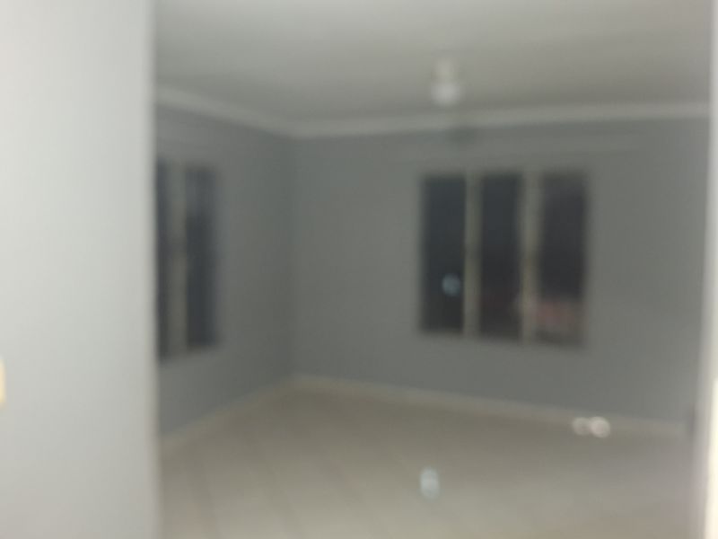 An empty living room area featuring tiled flooring and a ceiling fan, presented in a blurry photograph.
