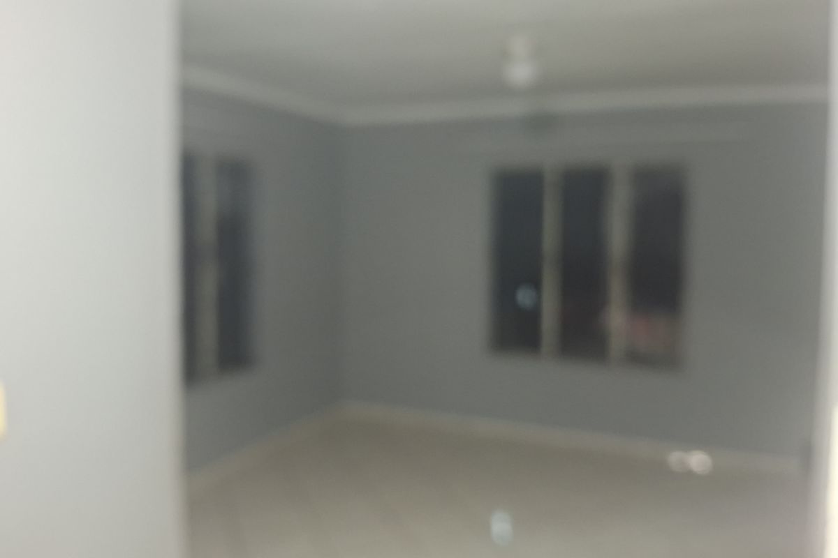An empty living room area featuring tiled flooring and a ceiling fan, presented in a blurry photograph.