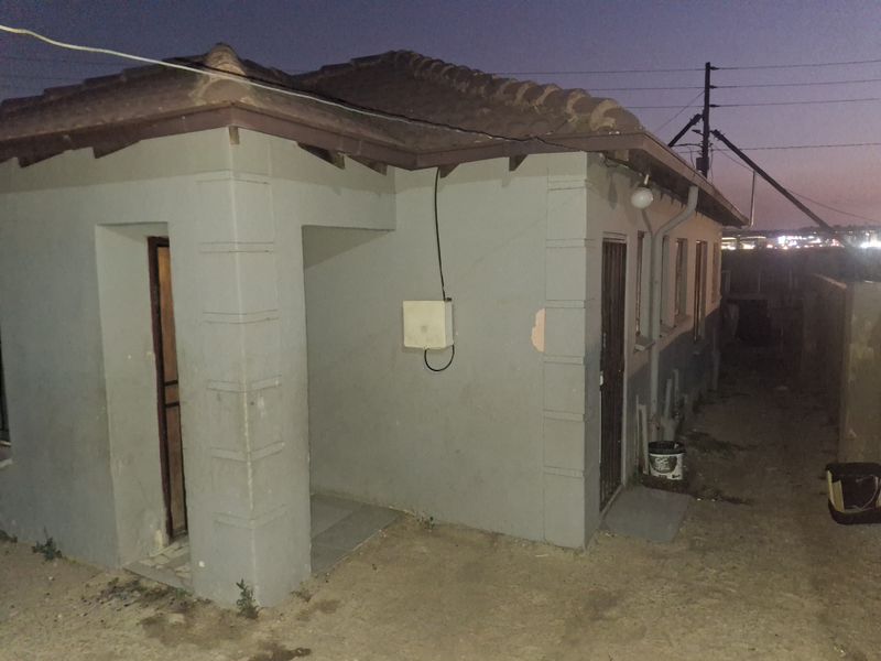 Rear exterior view of the property showing the building facade, tiled roof, and security access points at dusk.