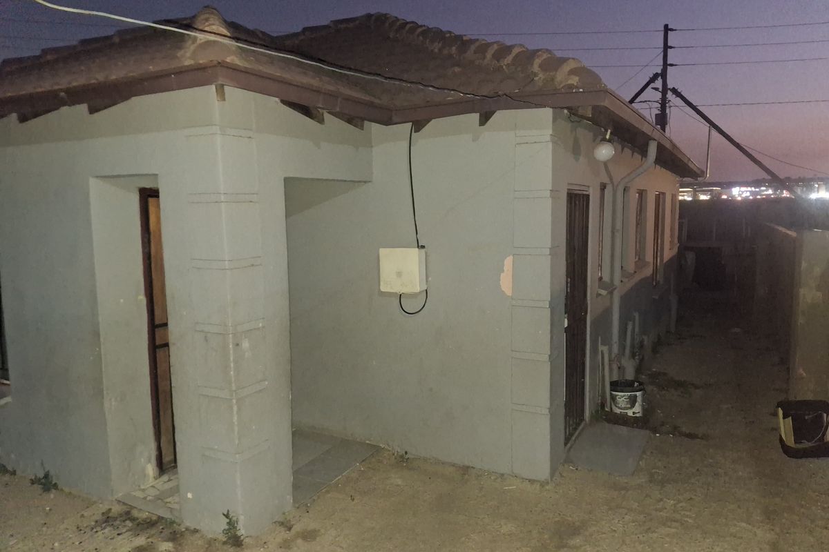 Rear exterior view of the property showing the building facade, tiled roof, and security access points at dusk.
