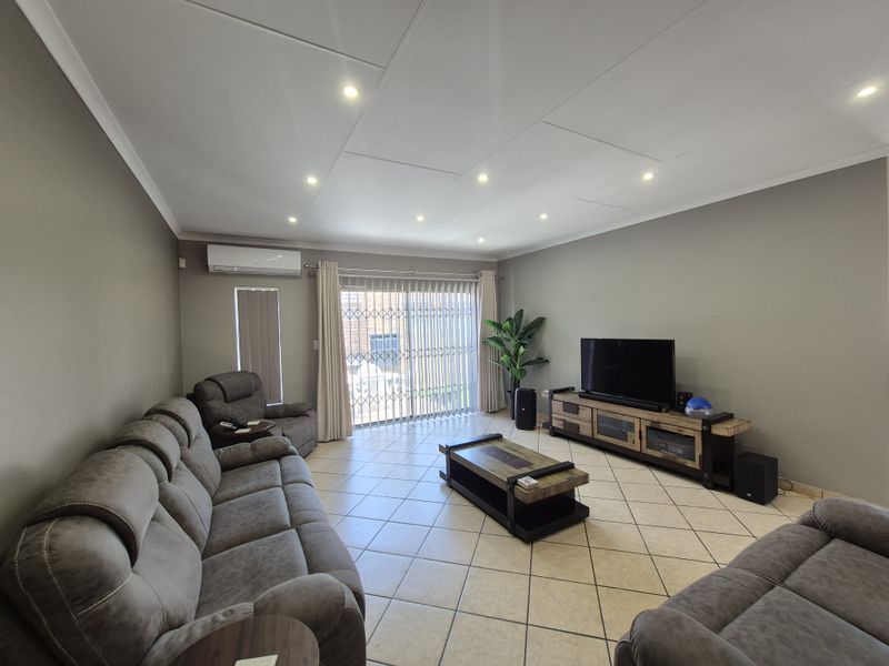 A well-maintained living room featuring tiled flooring, recessed downlighting, and a split-system air conditioner, with direct access to the exterior via a sliding door.