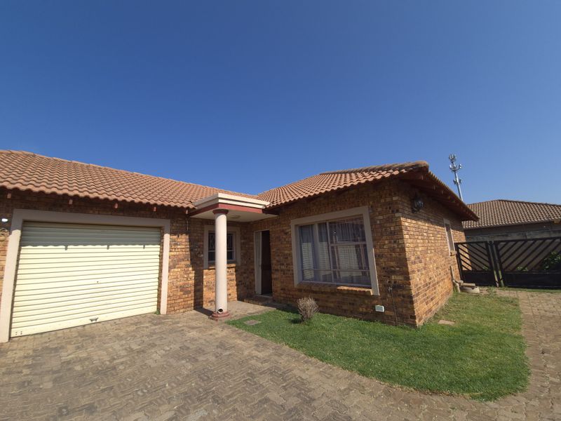 Front view of a face brick house featuring a single garage, paved driveway, and a covered entrance area.