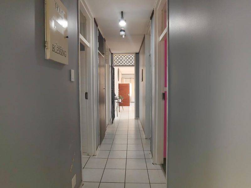A functional hallway featuring tiled flooring and multiple internal door access points, connecting various rooms within the home.