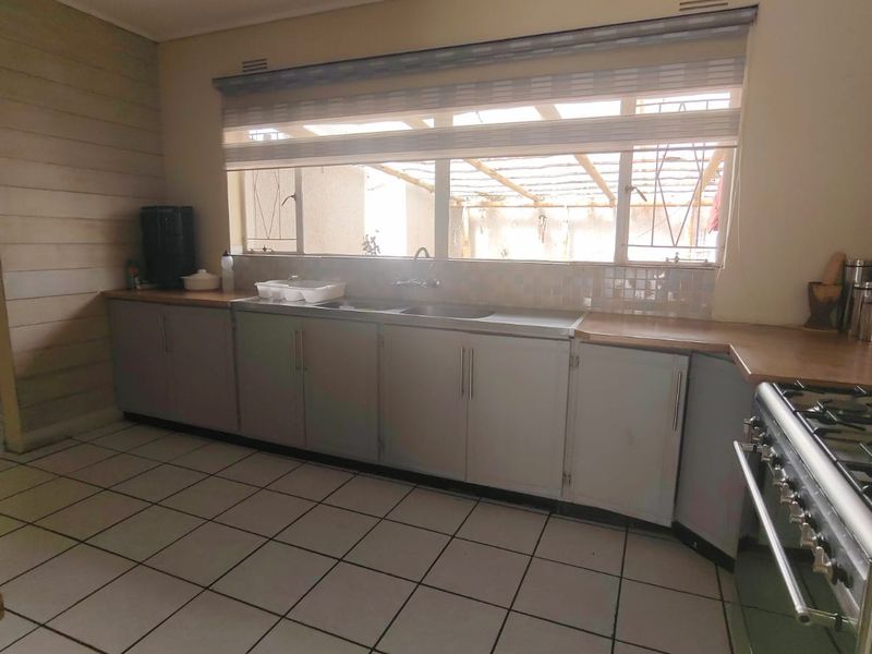 A functional kitchen featuring tiled flooring, built-in cabinetry, a stainless steel sink, and a gas stove with a tiled backsplash.