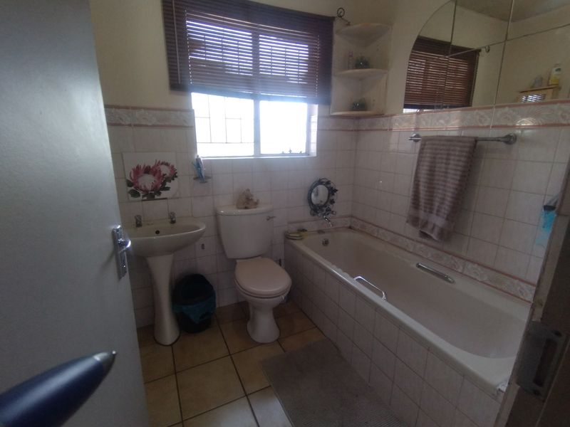 A dated bathroom featuring a pedestal basin, toilet, and bathtub with tiled walls and flooring, requiring modernization to improve aesthetic appeal.