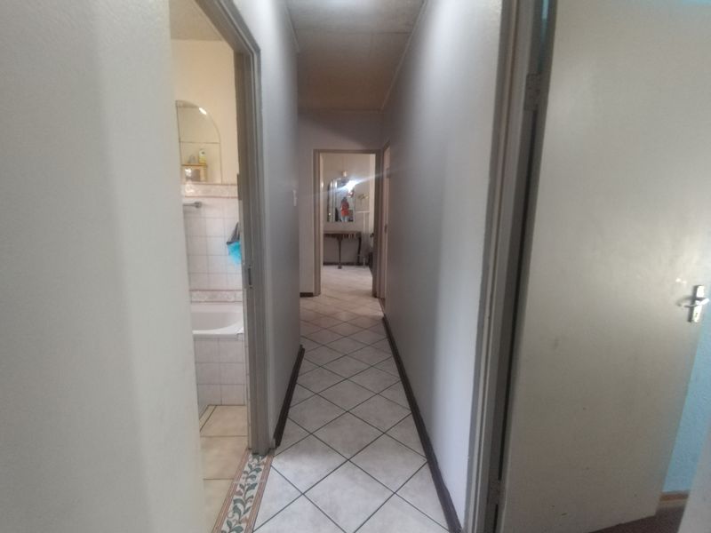 A functional hallway with tiled flooring connecting multiple rooms, featuring neutral wall tones and standard internal door access.