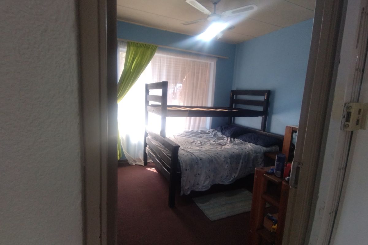 A bedroom featuring carpet flooring and a ceiling fan, viewed from the doorway with natural light entering through the window.