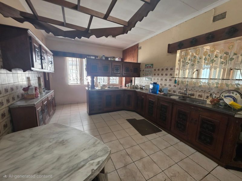 Spacious kitchen featuring extensive built-in wooden cabinetry, tiled splashbacks, and a double sink, offering a functional layout with significant potential for modern renovation.